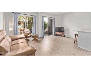 Bright living room featuring neutral walls, wood-look floors, and sliding glass doors to a treed outdoor area at 1006 E Osborn Rd # B, Phoenix, AZ 85014