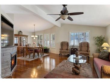 Inviting living room features hardwood floors, fireplace, and natural light from plantation shutters at 17200 W Bell Rd # 1748, Surprise, AZ 85374