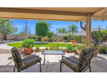 Inviting covered back patio with comfortable seating and a view of the lush green backyard at 6401 N 82Nd Way, Scottsdale, AZ 85250
