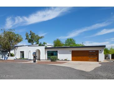 Stunning white exterior with modern wood garage door and desert landscaping under a blue sky at 856 E Village Cir S Dr, Phoenix, AZ 85022