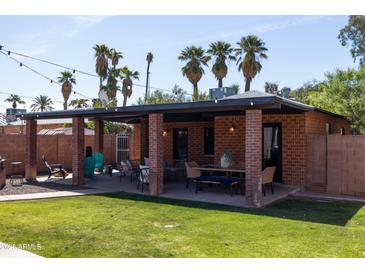 Inviting backyard with a covered patio, outdoor seating, and manicured lawn with mature landscaping, offering a private oasis at 1546 W Culver St, Phoenix, AZ 85007