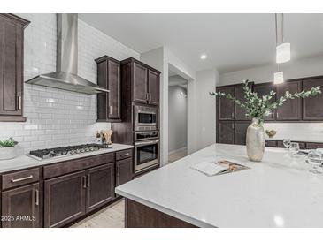 Gourmet kitchen featuring a gas cooktop, subway tile backsplash, and stainless steel hood at 18025 N 65Th Pl, Phoenix, AZ 85054