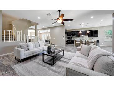 Inviting living room with modern ceiling fan, sleek coffee table, and comfortable seating area at 25449 N 102Nd Dr, Peoria, AZ 85383