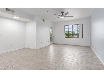 Bright living room showcasing tile flooring, a ceiling fan, and natural light from the window at 5302 E Van Buren St # 2015, Phoenix, AZ 85008