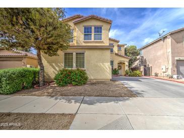 Two-story home with a stucco exterior, landscaping, and a tree in the front yard on a sunny day at 17374 W Adams St, Goodyear, AZ 85338