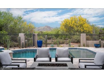 Inviting pool area featuring a sparkling pool, comfortable lounge chairs, and lush desert landscaping with mountain views at 39847 N 105Th Pl, Scottsdale, AZ 85262