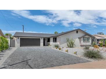 Charming single-story home with a spacious driveway, desert landscaping, and a modern garage door at 8316 E Glenrosa Ave, Scottsdale, AZ 85251