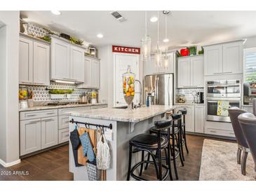 An open kitchen with grey cabinets, granite countertops, an island and stainless steel appliances at 13088 N 91St Dr, Peoria, AZ 85381