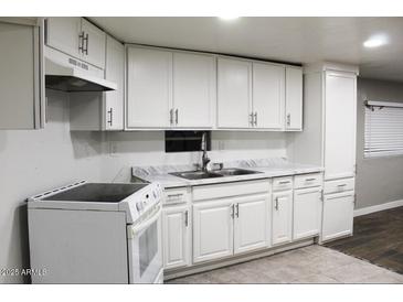 Well-lit kitchen featuring white cabinets, an electric stove, and marble-look countertops at 29 W Southern Ave # 28, Mesa, AZ 85210