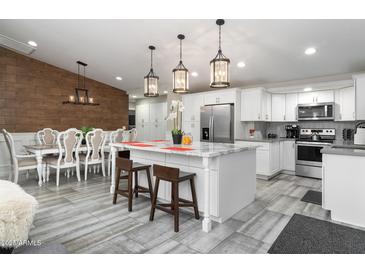 Spacious kitchen with a marble island, stainless steel appliances, and an adjacent dining area featuring wood accent wall at 2025 N 87Th Way, Scottsdale, AZ 85257