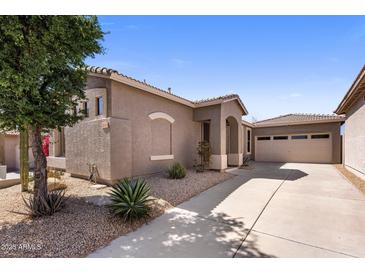 Tan home exterior with tile roof, desert landscaping, and a spacious driveway leading to the attached garage at 2610 W Sat Nam Way, Phoenix, AZ 85086