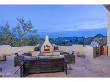 Outdoor patio featuring cozy seating, a fireplace, built-in grill and stunning mountain views at 28437 N 112Th Way, Scottsdale, AZ 85262