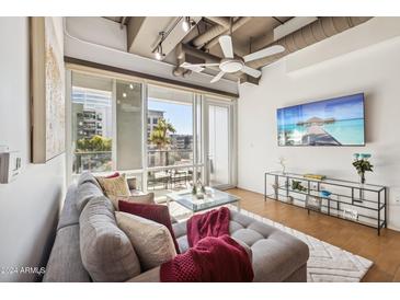 Bright living room with exposed ductwork, large windows, and a comfortable gray couch at 1 E Lexington Ave # 302, Phoenix, AZ 85012