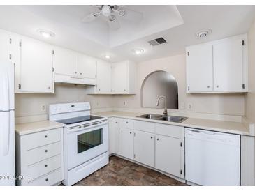 Bright kitchen with white cabinets, appliances, and a neutral countertop offers a clean and functional space at 1217 N Miller Rd # 23, Scottsdale, AZ 85257
