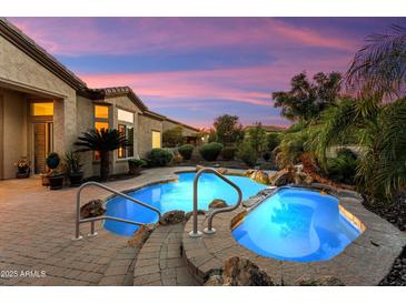Beautiful backyard pool and spa area with rock waterfall feature and lush desert landscaping at 12976 W Plum Rd, Peoria, AZ 85383