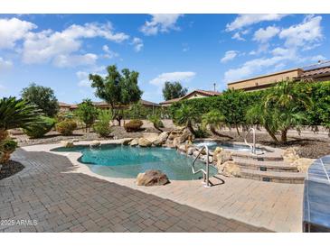 Resort-style pool with waterfall, spa, and lush landscaping in a private backyard oasis at 12976 W Plum Rd, Peoria, AZ 85383