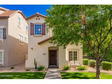 Charming two-story home features a well-manicured lawn, a front porch bench, and desert landscaping at 1322 S Owl Dr, Gilbert, AZ 85296