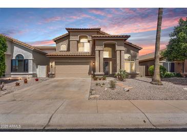 Charming two-story home featuring stucco siding, a two-car garage, desert landscaping, and a tiled roof at 14393 N 101St St, Scottsdale, AZ 85260