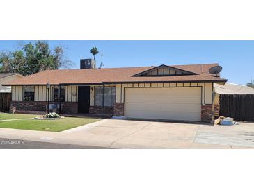 Charming single-story home featuring a well-manicured lawn, attached garage and neutral-colored exterior at 5347 W Seldon Ln, Glendale, AZ 85302