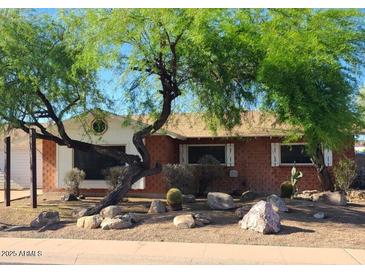 Charming single-story home featuring a desert-landscaped yard and mature trees at 8220 E Montecito Ave, Scottsdale, AZ 85251