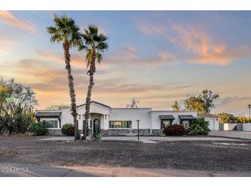 Beautiful home exterior features palm trees, stone accents, and manicured landscaping in a tranquil setting at 12210 N 67Th St, Scottsdale, AZ 85254