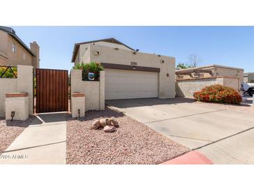 View of the home's driveway and the attached two-car garage with a decorative wooden gate at 630 E Jensen St # 116, Mesa, AZ 85203