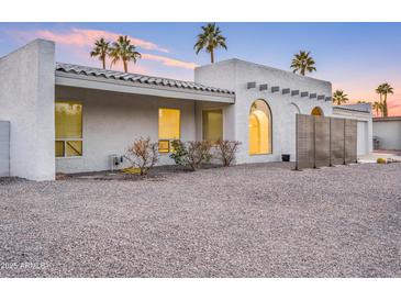 Charming, single-story home with stucco walls and lush palm trees against a beautiful dusk sky at 6739 E Thunderbird Rd, Scottsdale, AZ 85254