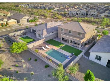 A bird's eye view of a property's backyard including a pool with lounge chairs, a barbeque, and a grassy area at 18381 W La Senda Dr, Surprise, AZ 85387