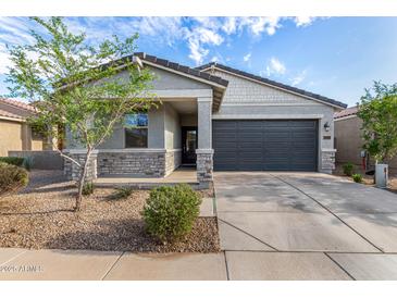 Charming single-story home with a two-car garage, stone accents, and desert landscaping at 39959 W Williams Way, Maricopa, AZ 85138