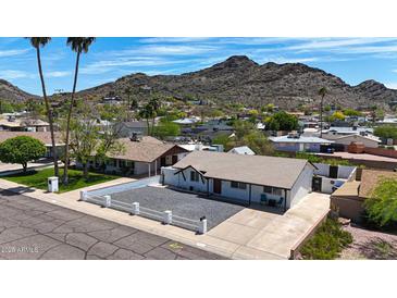 Charming single-story home featuring a rock driveway and a bright white fence, nestled in a peaceful neighborhood with a mountain backdrop at 1511 E Carol Ave, Phoenix, AZ 85020