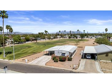 Well-kept single-story home with a carport, lush green lawn and palm trees with mountain views in the distance at 1641 S Sossaman Rd, Mesa, AZ 85209