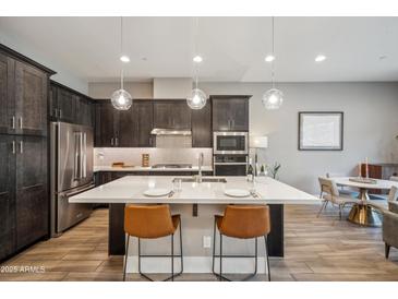 Modern kitchen with large island, stainless steel appliances, and dark wood cabinets at 7464 E Paraiso Dr, Scottsdale, AZ 85255