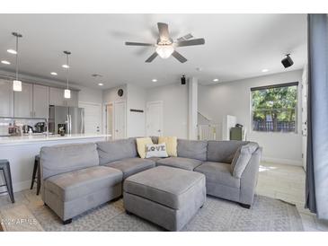 Bright living room featuring a comfortable gray sectional sofa and an open floor plan at 7531 E Billings St # 116, Mesa, AZ 85207