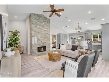 Bright living room features a stone fireplace, ceiling fan and neutral furniture at 9223 E Camino Del Santo --, Scottsdale, AZ 85260
