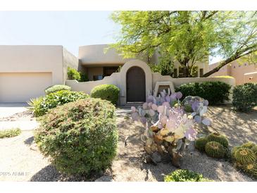 Charming home with desert landscaping, mature trees, cacti, and a decorative front gate entry at 10795 E Sutherland Way, Scottsdale, AZ 85262