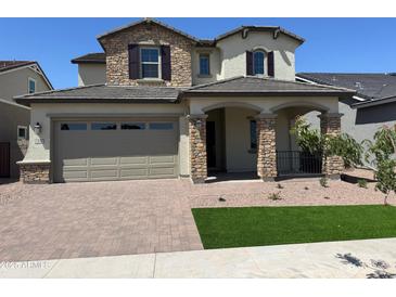 Charming two-story home featuring a stone facade, a two-car garage, and manicured landscaping at 15626 W Georgia Dr, Surprise, AZ 85379