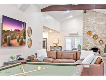 Open living room featuring vaulted ceilings, a brick fireplace, leather seating, and a billiard table at 16436 N 64Th Pl, Scottsdale, AZ 85254