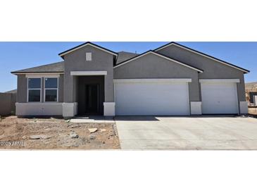 Charming single-story home featuring a two-car garage and neutral-colored stucco exterior under a clear, blue sky at 5865 E Axle Ln, San Tan Valley, AZ 85140