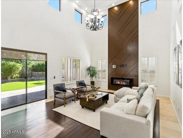 Open-concept living room featuring a modern fireplace, soaring ceilings, and backyard access at 3221 E Lynx Pl, Chandler, AZ 85249