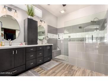 Sleek primary bath with dual vanities, soaking tub, and glass-enclosed shower with grey tile at 4706 E Des Moines St, Mesa, AZ 85205