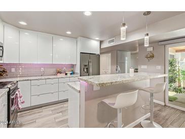 This updated kitchen features modern white cabinets, stainless steel appliances, and a breakfast bar with seating at 5913 E Thomas Rd, Scottsdale, AZ 85251