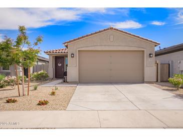 Charming single-story home showcasing a two-car garage and low-maintenance desert landscaping under a bright blue sky at 17431 W Via De Luna Dr, Surprise, AZ 85387