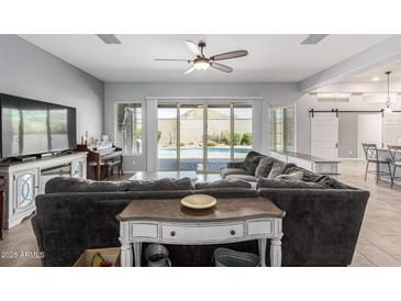 Spacious living room with a sectional sofa and a view of the pool through sliding glass doors at 28623 N 66Th Ave, Phoenix, AZ 85083