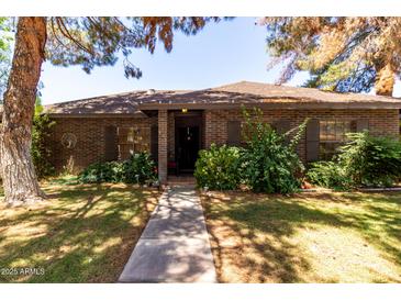 Charming single-story brick home featuring mature trees, a well-maintained lawn, and welcoming front entrance at 930 E Page St, Gilbert, AZ 85234