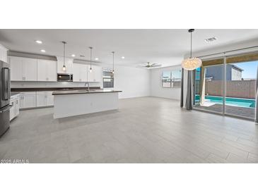 Open-concept living area with a modern kitchen, stylish pendant lighting, and a sliding glass door at 14413 W Eugene Ter, Surprise, AZ 85379
