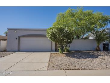 Beige single story home with a two-car garage, desert landscaping and blue sky at 1450 E Topeka Dr, Phoenix, AZ 85024