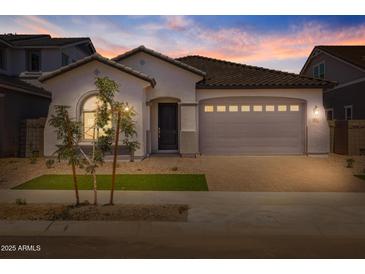 Charming single-story home with a manicured front yard, tile roof and a two car garage at dusk at 15620 W Georgia Dr, Surprise, AZ 85379