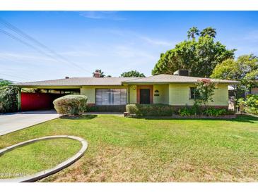 Charming home featuring a well-manicured front lawn and welcoming curb appeal on a sunny day at 1941 E Hazelwood St, Phoenix, AZ 85016