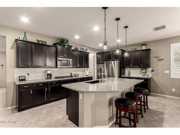 Modern kitchen featuring dark wood cabinets, granite countertops, and a central island with bar stool seating at 2440 W Arroyo Way, San Tan Valley, AZ 85144