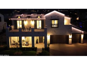 Striking two-story home exterior featuring well-manicured lawn and a welcoming facade lit with decorative lights at 3669 E Boot Track Trl, Gilbert, AZ 85296